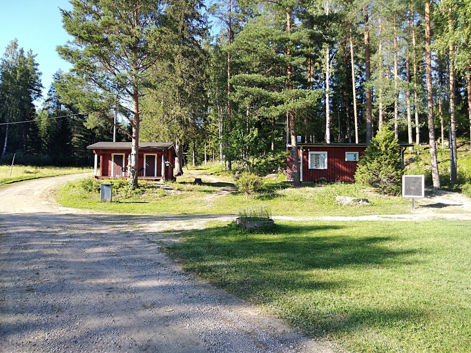 Kaksi punaista aittaa soratien varrella mäntyjen keskellä Karijärvi Campingin alueella.